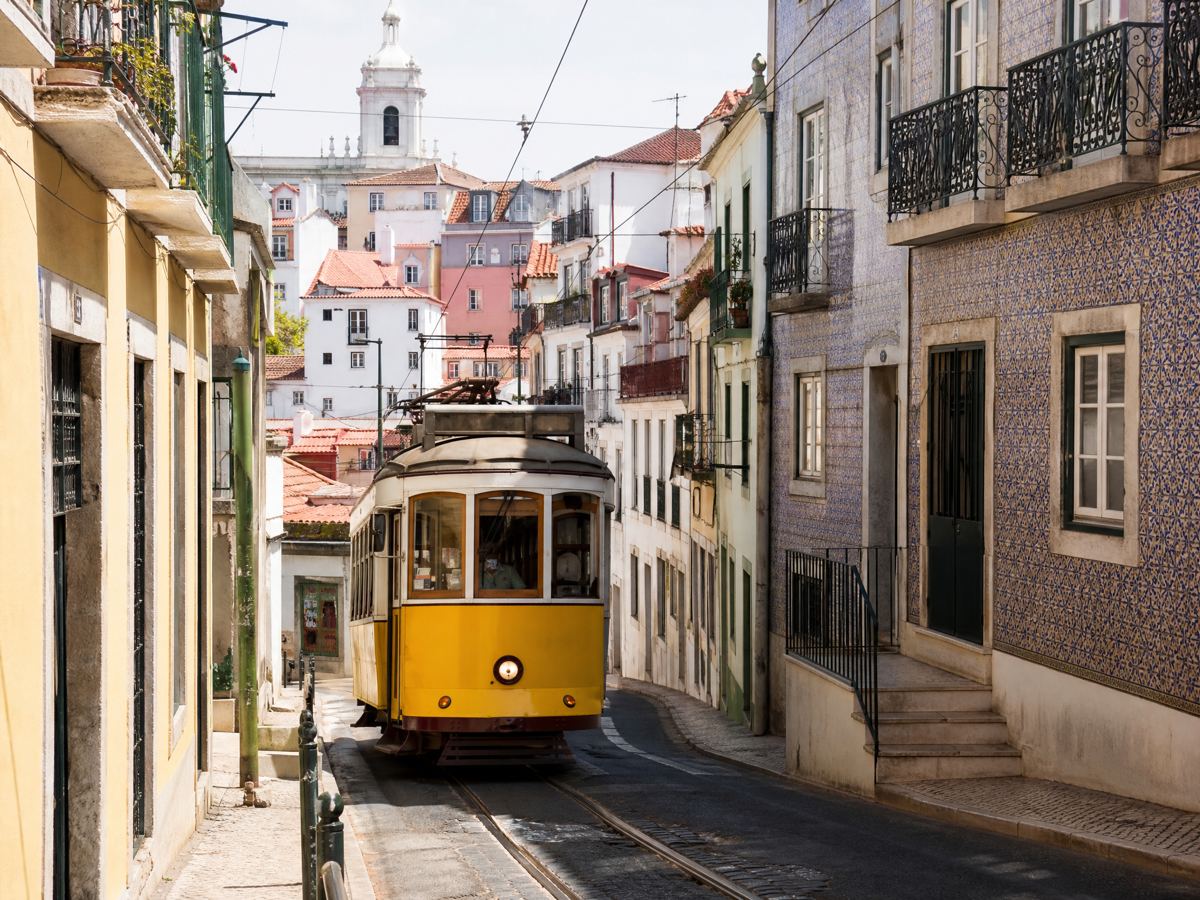 Tranvía amarillo 28 en una calle empinada en Alfama, Lisboa